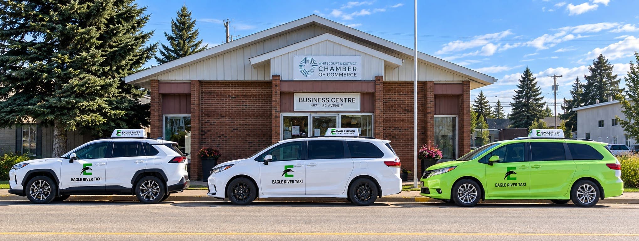 White and green Eagle River Cabs vehicles outside a community building.